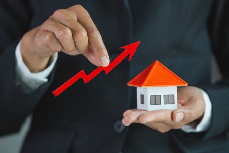 homem segurando miniatura de casa em uma mão e na outra uma linha de progressão representando o marketing imobiliário