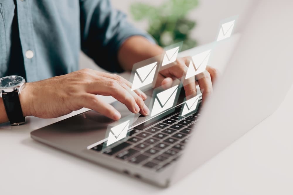 homem utilizando notebook com e-mails saindo da tela para representar E-mail marketing para incorporadoras