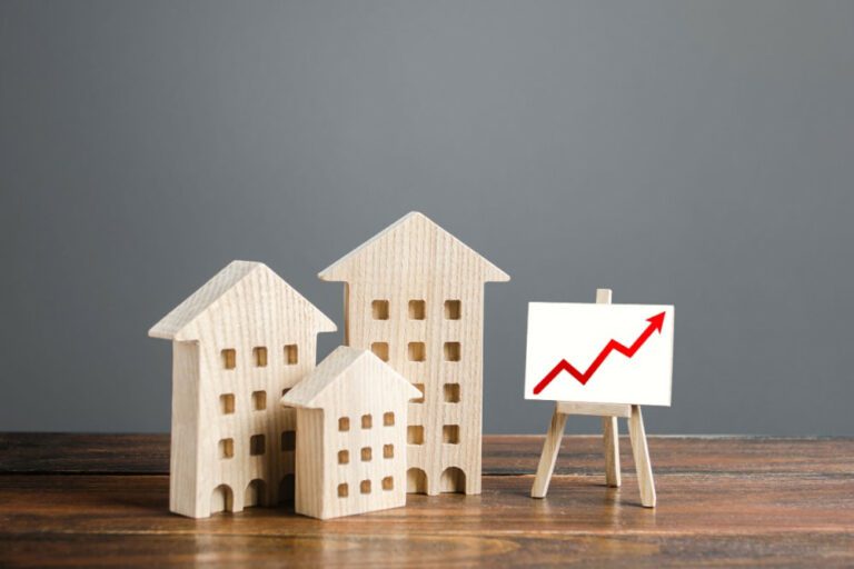 Maquete de três prédios em madeira e um cavalete com uma tela. Na tela, há um gráfico vermelho indicando crescimento.