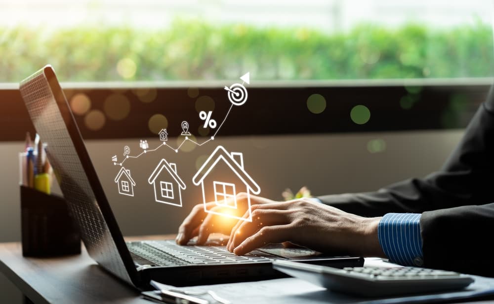 Profissional digitando em um laptop com ícones digitais de imóveis e estratégias de marketing online, representando a combinação de estratégias online e offline para lançamentos imobiliários.